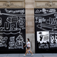 A woman wearing a protective face mask walks past graffiti on boarded up and closed storefronts in the Soho neighborhood of Manhattan during the outbreak of the coronavirus disease (COVID-19) in New York City, New York, U.S., May 26, 2020. REUTERS/Mike Segar